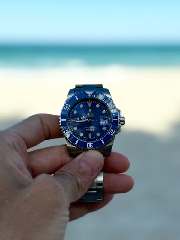 Ali'i Watch Company Waterman blue watch held against the ocean