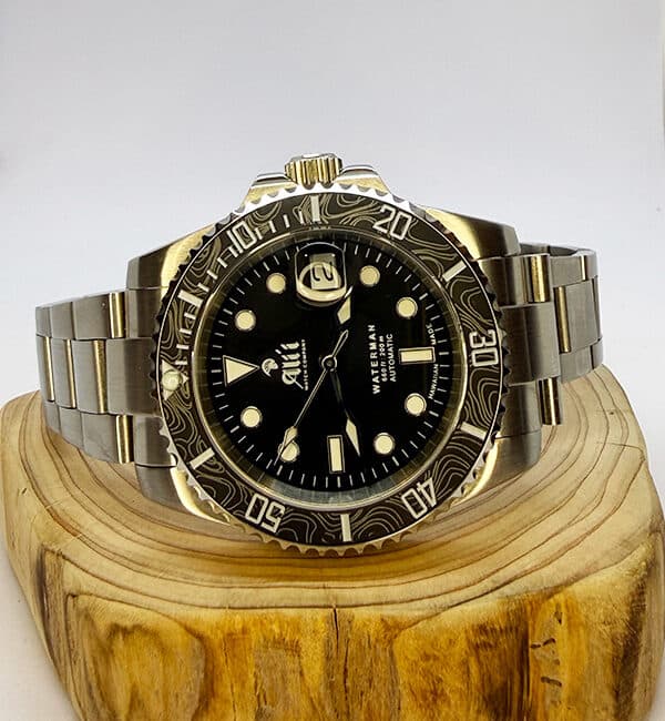 Ali'i Watch Company Waterman watch with a black bezel and carbon fiber bezel with silver minute markers sits on a piece of wood.