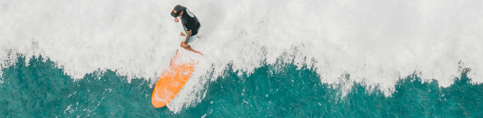 Surfer riding a wave with an orange surfboard